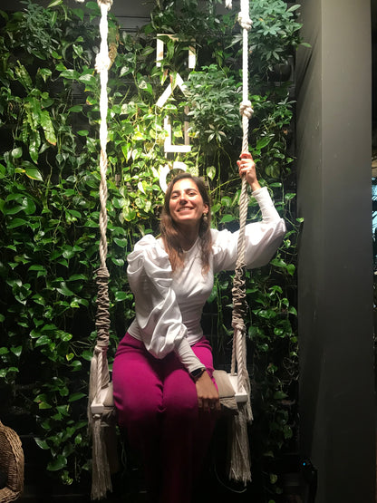 Model sitting on a swing using Blouse Tibau White with Pantalon Extremoz Mauve